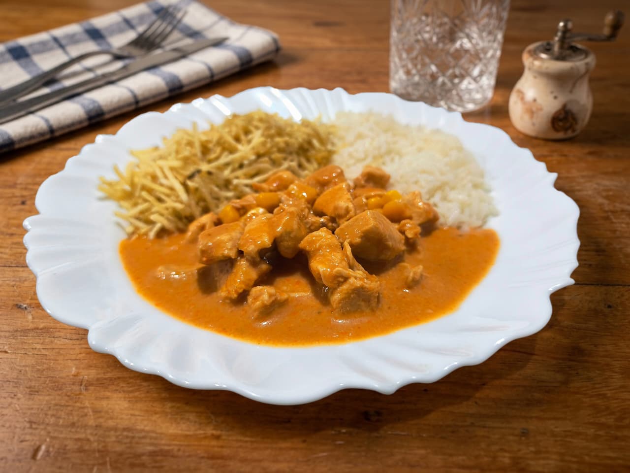 Prato fundo farto servido com strogonoff de frango em molho cremoso rosado, acompanhado de arroz branco soltinho e coberto com bastante batata palha. Ao lado, um copo suado de Guaraná Antarctica gelado.